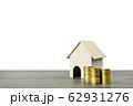 A small wooden house model with stack of coins. 62931276