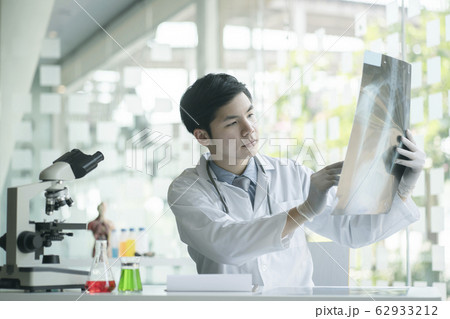 Doctor checking examining chest x-ray film of patient at ward hospital. Doctor checking examining chest x-ray film of patient at ward hospital. 62933212
