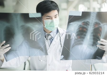 Doctor checking examining chest x-ray film of patient at ward hospital.  62933214