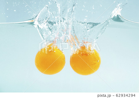 Citrus freshness. Pair of tasty lemons dropping into water with splash on blue background Citrus freshness. Pair of tasty lemons dropping into water with splash on blue background 62934294
