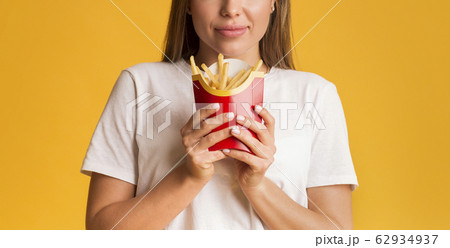 Big French Fries Serving In Hands Of Unrecognizable Happy Woman, Panorama 62934937