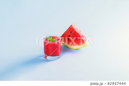Summer drink, watermelon smoothie in a glass with fresh watermelon slices on a pastel blue background 62937444