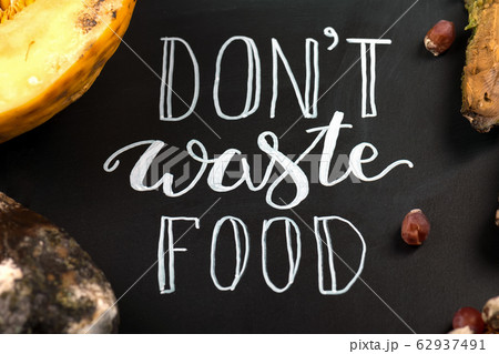 Close up of a chalkboard with Don't waste food lettering and rotten fruits. Selective focus. 62937491