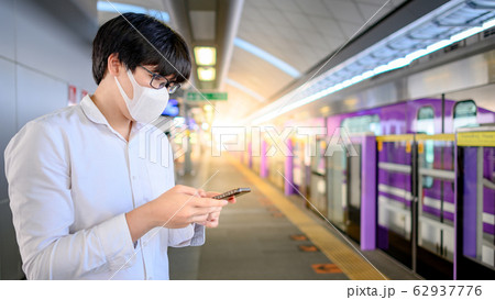 Man wearing mask using phone at skytrain station 62937776