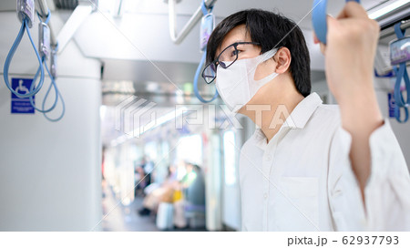 Asian man wearing mask holding handrail on 62937793