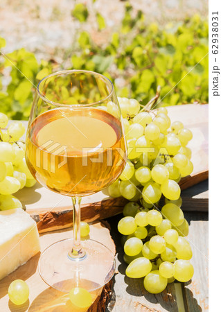 Beautiful still life with amber wine in glasses on the nature: a bright summer drink with cheese and grapes in a rustic style. Beautiful still life with amber wine in glasses on the nature: a bright summer drink with cheese and grapes in a rustic style. 62938031