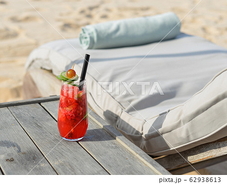 Glass of fruit juice on a beach table 62938613