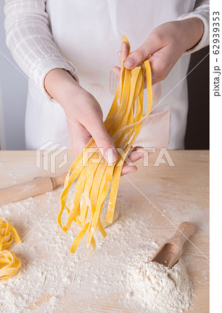 A young woman is holding fresh homemade pasta - Italian tagliatelle. Italian pasta made from flour, water and eggs. 62939353