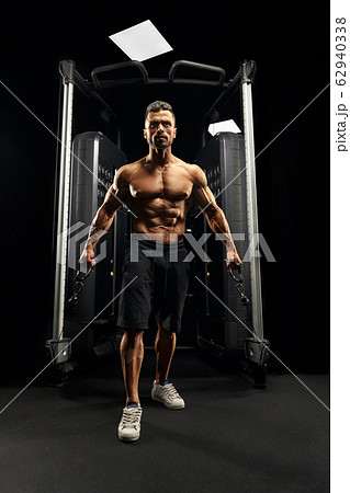 Muscular bodybuilder doing crossover cable exercise. Muscular bodybuilder doing crossover cable exercise. 62940338