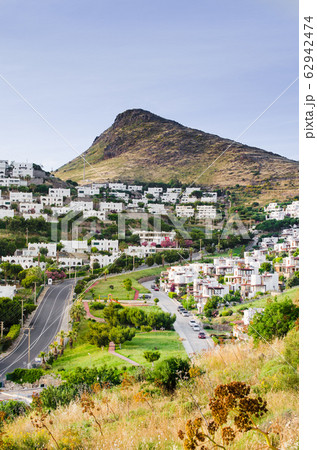 View on traditional white cubic houses, green trees, brown rocks and the road. Bodrum town, Turkey. 62942474