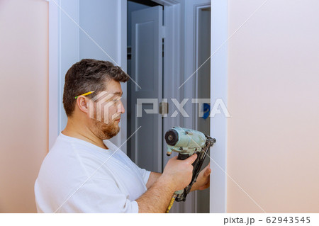 Construction handyman using air nail gun Construction handyman using air nail gun 62943545