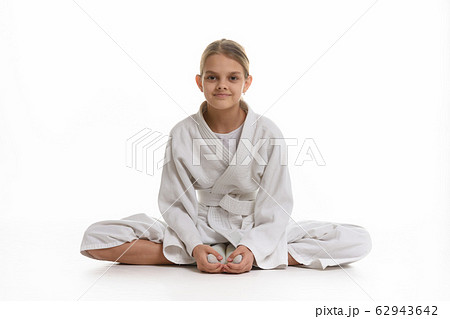 Sporting girl in keikogi sits on the floor, white 62943642