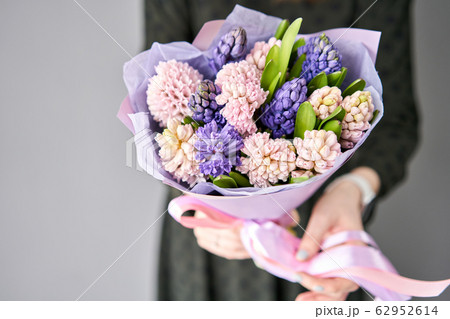 Young happy woman holding a beautiful bunch of colorful hyacinths in her hands. Present for a smiles girl. Flowers bouquet. Young happy woman holding a beautiful bunch of colorful hyacinths in her hands. Present for a smiles girl. Flowers bouquet. 62952614