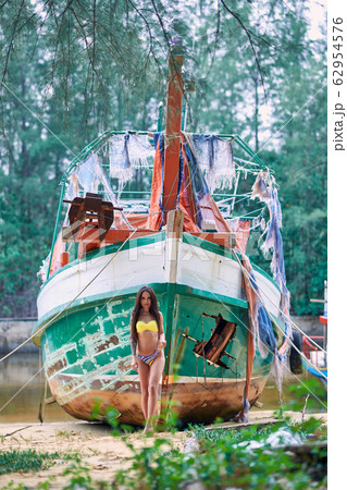 Model in bikini posing with old abandoned fishing Model in bikini posing with old abandoned fishing 62954576