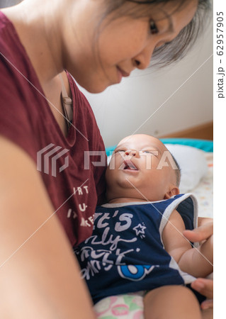 Asian women holding smiling infant boy in bedroom Asian women holding smiling infant boy in bedroom 62957905