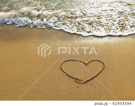 Heart drawn on the sand of a sea beach with white wave at sunset time. Heart drawn on the sand of a sea beach with white wave at sunset time. 62958384