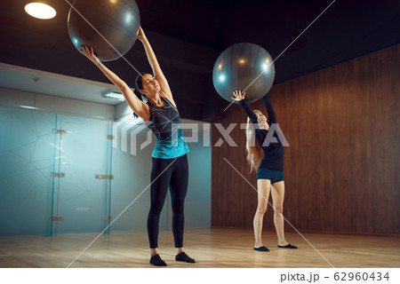 Two women, pilates training with balls in gym Two women, pilates training with balls in gym 62960434