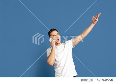 Caucasian young man's portrait on blue studio background Caucasian young man's portrait on blue studio background 62960556