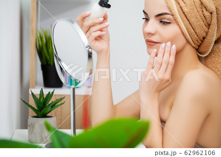 Woman getting ready for work doing morning makeup in bathroom mirror at home Woman getting ready for work doing morning makeup in bathroom mirror at home 62962106