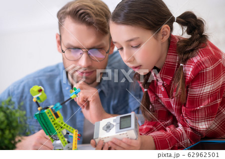 Girl holding control unit, teacher sitting and touching chin 62962501