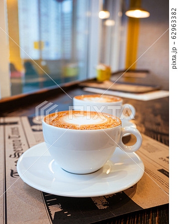 Two cups of cappuccino on a table in a cafe. drawing heart on Latte coffee froth. Delicious coffee for breakfast Two cups of cappuccino on a table in a cafe. drawing heart on Latte coffee froth. Delicious coffee for breakfast 62963382