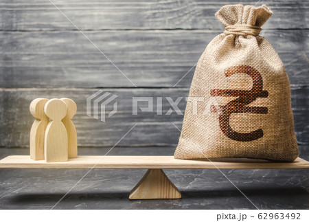 Ukrainian hryvnia UAH symbol on money bag and people on scales. concept attracting investment, business cooperation, crowdfunding startup. Staff salary specialist services cost. Solvency, taxpayers 62963492