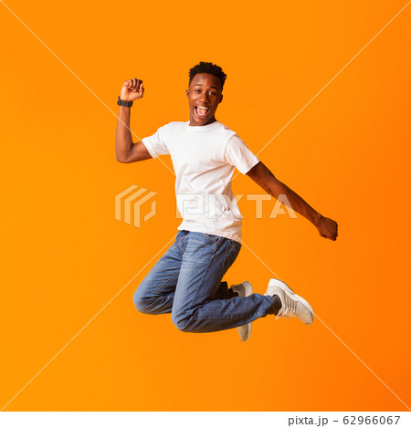 Excited screaming african man jumping while celebrating Excited screaming african man jumping while celebrating 62966067