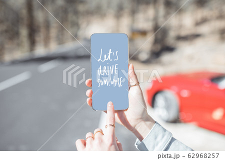 Holding smart phone with a text about traveling Holding smart phone with a text about traveling 62968257