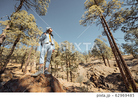 Woman hiking in the forest highly in the mountains on a volcanic rocks Woman hiking in the forest highly in the mountains on a volcanic rocks 62969485