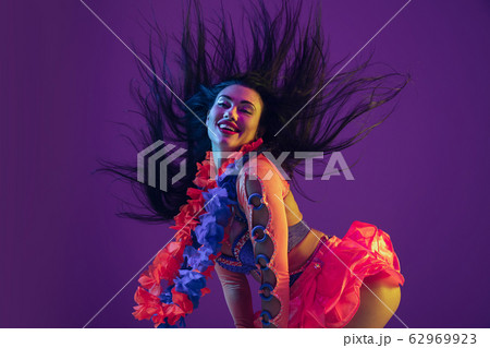 Attractive hawaiian brunette model on purple studio background in neon light 62969923