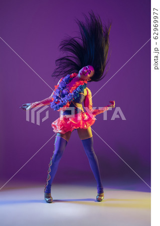 Attractive hawaiian brunette model on purple studio background in neon light 62969977