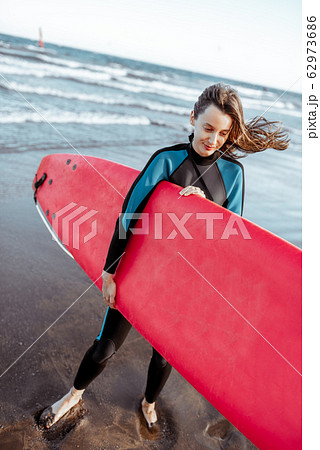 Woman with surfboard on the beach Woman with surfboard on the beach 62973686
