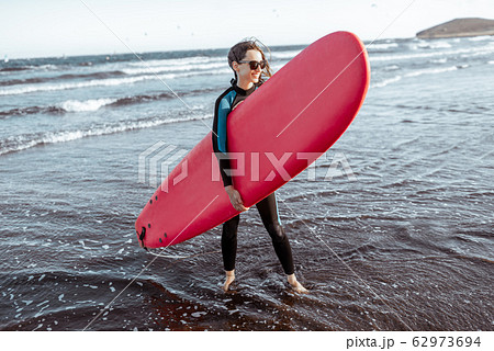 Woman with surfboard on the beach 62973694