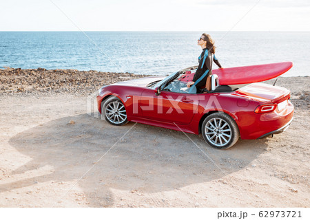 Woman with surfboard on the car near the oceanの写真素材 [62973721
