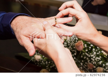 Woman putting a wedding ring on a man's finger at a wedding ceremony, romantic concept, bride and groom, close up 62974236