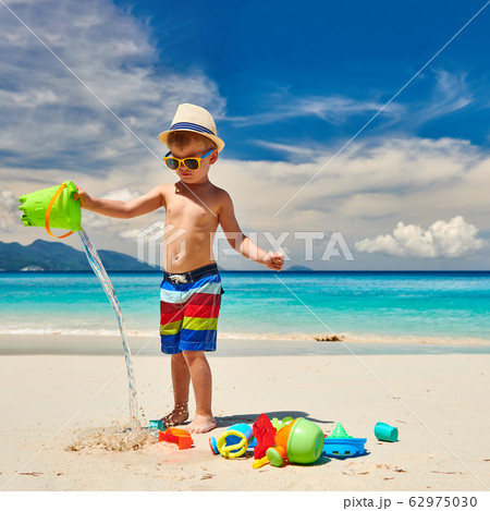 Three year old toddler playing on beach Three year old toddler playing on beach 62975030