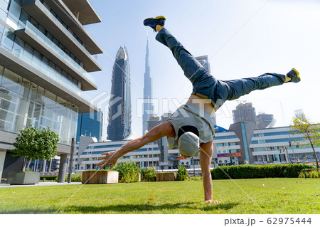 Acrobat keep balance on one hand with blurred Dubai cityscape. Concept of modern, business and Acrobat keep balance on one hand with blurred Dubai cityscape. Concept of modern, business and 62975444
