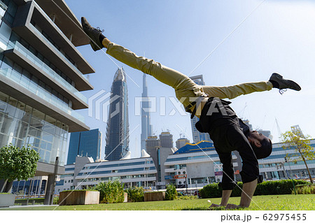 Acrobat keep balance one the hands with blurred Dubai cityscape. Concept of modern, business and Acrobat keep balance one the hands with blurred Dubai cityscape. Concept of modern, business and 62975455