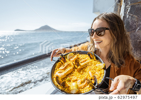 Woman eating sea food near the ocean Woman eating sea food near the ocean 62975497