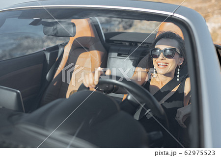 Woman driving a cabriolet near the ocean Woman driving a cabriolet near the ocean 62975523