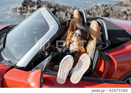 Woman enjoying summer vacation while traveling by car Woman enjoying summer vacation while traveling by car 62975580