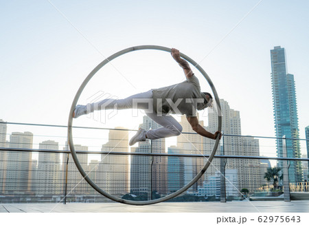 Cyr Wheel artist with cityscape background of Dubai during sunset Cyr Wheel artist with cityscape background of Dubai during sunset 62975643
