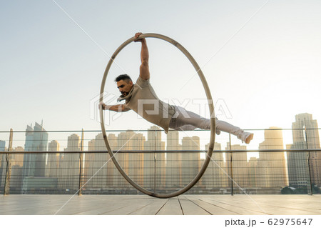 Cyr Wheel artist with cityscape background of Dubai during sunset 62975647