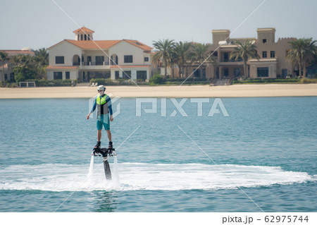 Water extreme sport. The guy is flying at the aquatic flyboard. Extreme rest on the sea Water extreme sport. The guy is flying at the aquatic flyboard. Extreme rest on the sea 62975744