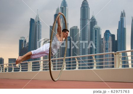 Cyr Wheel artist with cityscape background of Dubai during sunset 62975763