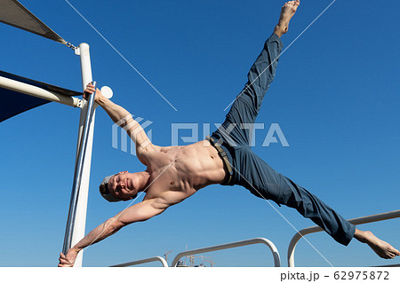 Muscular man doing workout on the street with blue sky on background in Dubai. Concept of healthy 62975872