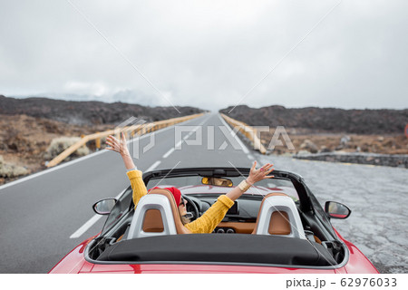 Woman traveling by cabriolet car on the volcanic valley Woman traveling by cabriolet car on the volcanic valley 62976033