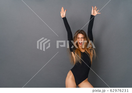 Young woman in a black bodysuit studio isolated on gray posing hands up Young woman in a black bodysuit studio isolated on gray posing hands up 62976231