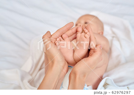 Young adult woman holding little new born baby feet in hands 62976297
