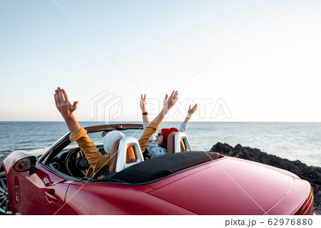 Couple driving convertible car near the ocean 62976880